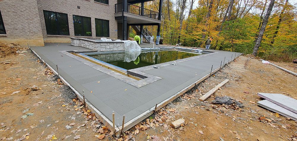 Modern house backyard with a rectangular concrete pool deck and partially filled swimming pool under construction