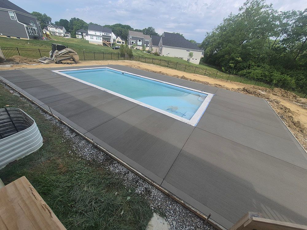 Backyard swimming pool surrounded by a large concrete deck under construction