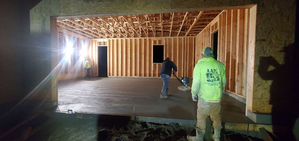 Workers inside a framed house under construction, lit at night