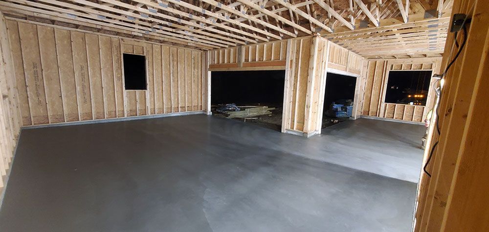 Unfinished interior room with exposed wood framing, concrete floor, and open window and doorway openings.