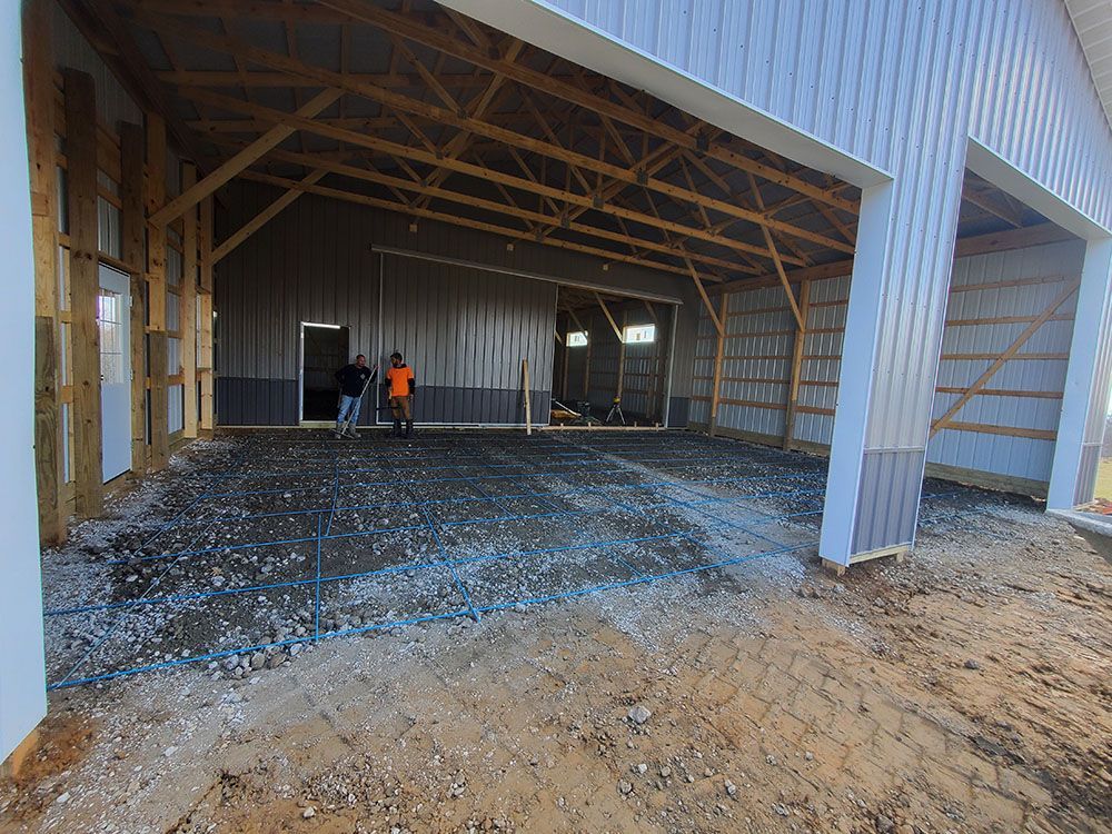 Partially built warehouse interior with metal framing and a worker in orange near the back wall