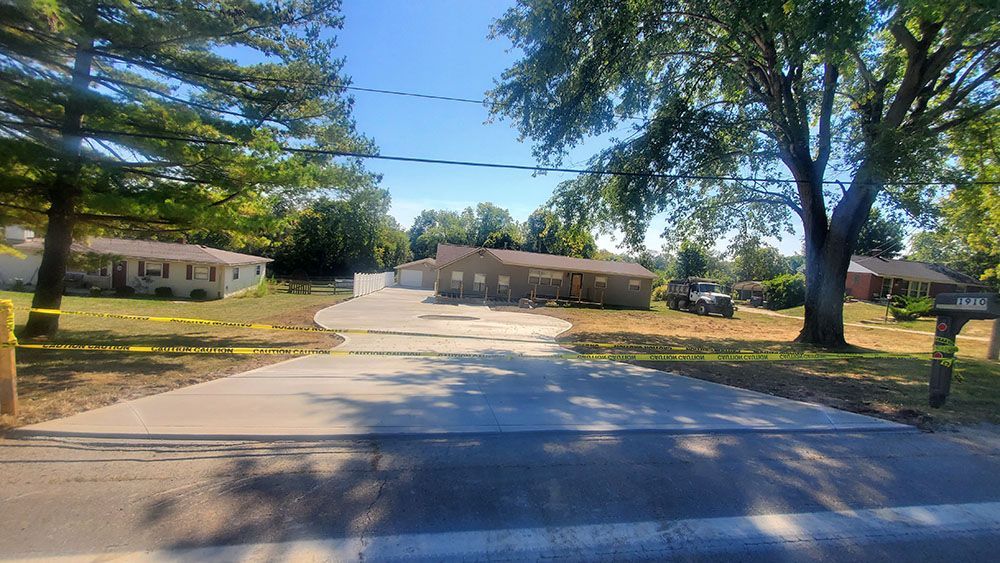 Tree-lined suburban street with single-story homes and a paved road in bright sunlight