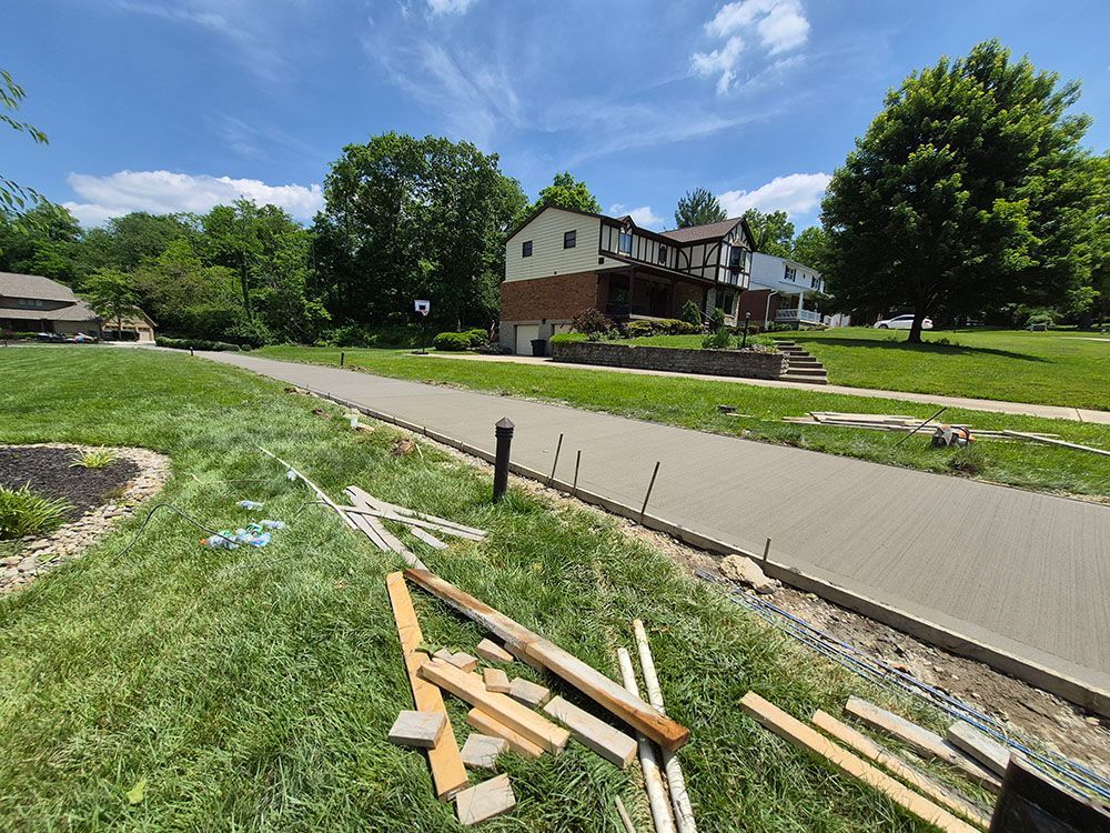 Suburban street with a house, green lawn, and scattered wooden boards under a blue sky