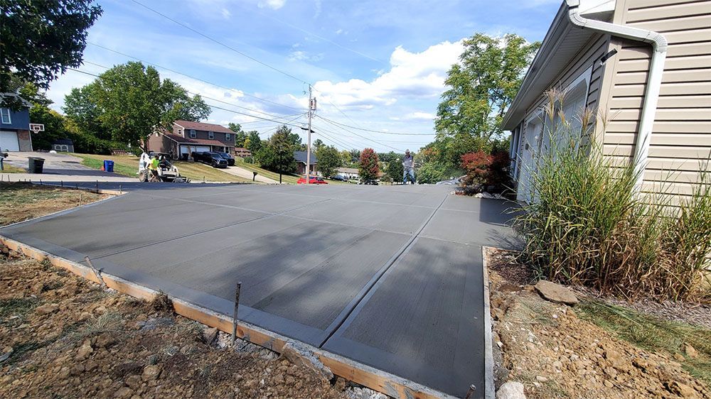 Freshly paved suburban street with a wide concrete driveway and houses on both sides