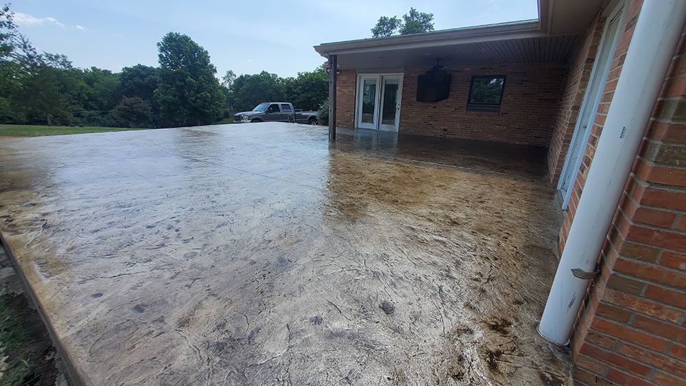 Floodwater surrounds a brick building and driveway, with muddy water covering the foreground.