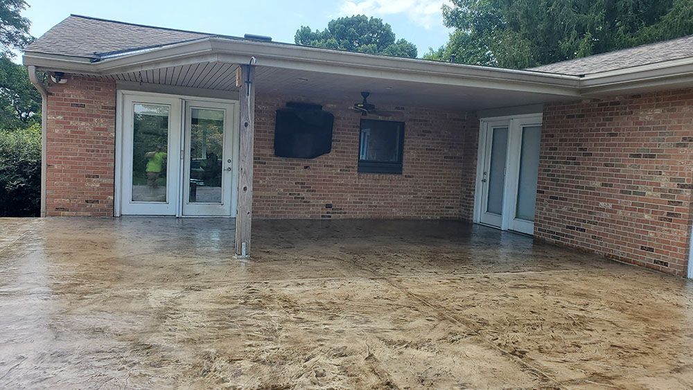 Brick house patio with wet concrete, double glass doors, and a covered porch.