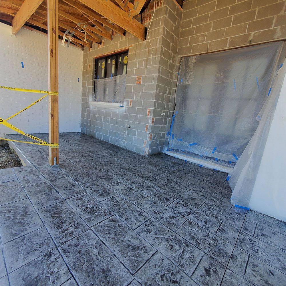 Interior construction area with tiled floor, cinderblock walls, exposed ceiling, and covered window and opening.