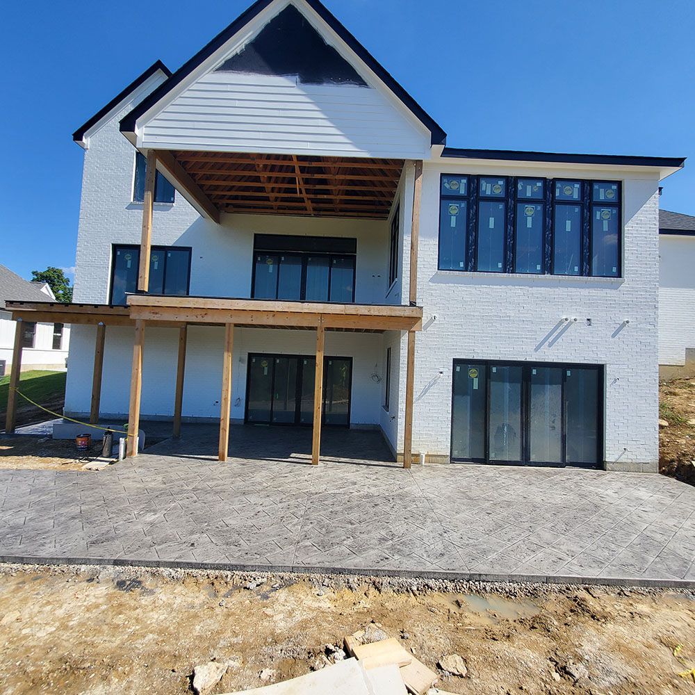 New two-story white house with dark-framed windows and a covered porch under construction.