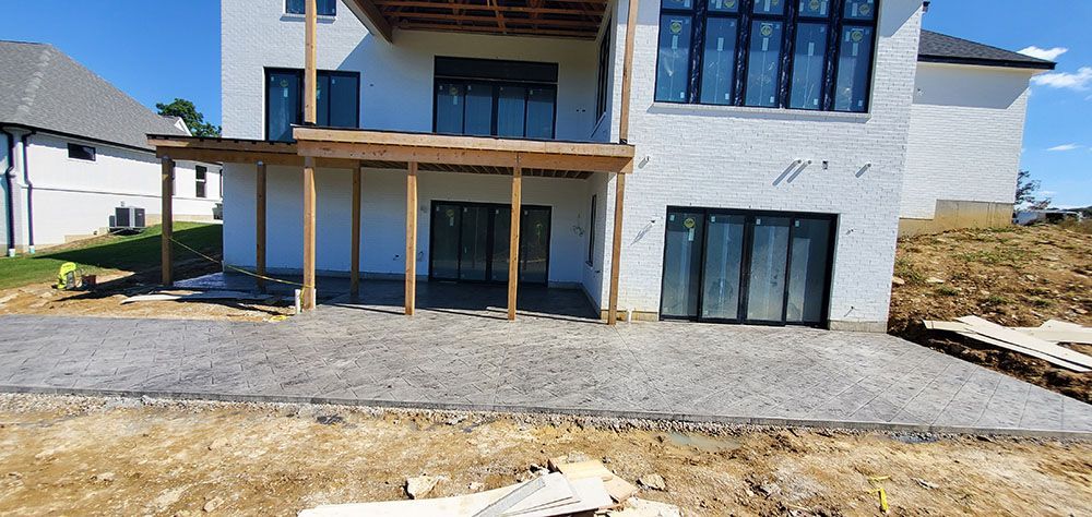 New house exterior with white siding, wood porch posts, and unfinished gravel driveway on a sunny day