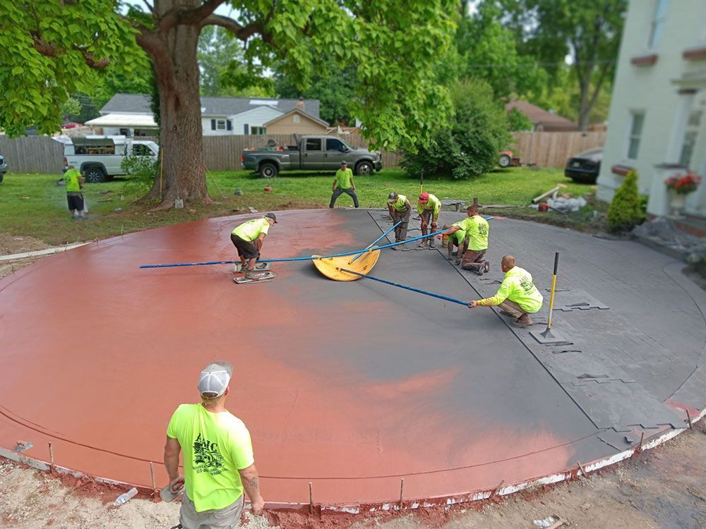 Workers smoothing a large red concrete slab in a residential street