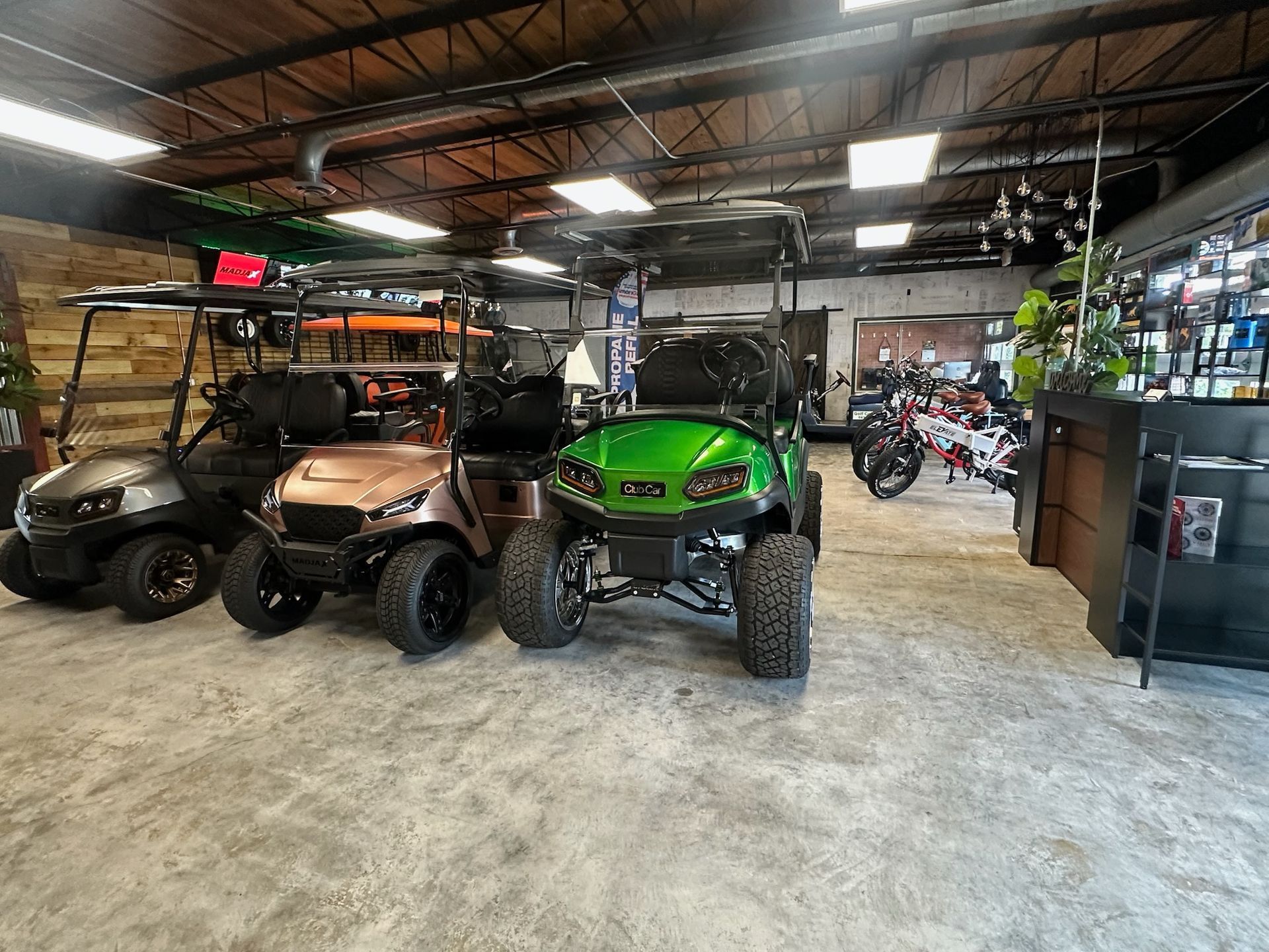 Off-road vehicles parked inside a large garage with tools, lights, and motorcycles in the background