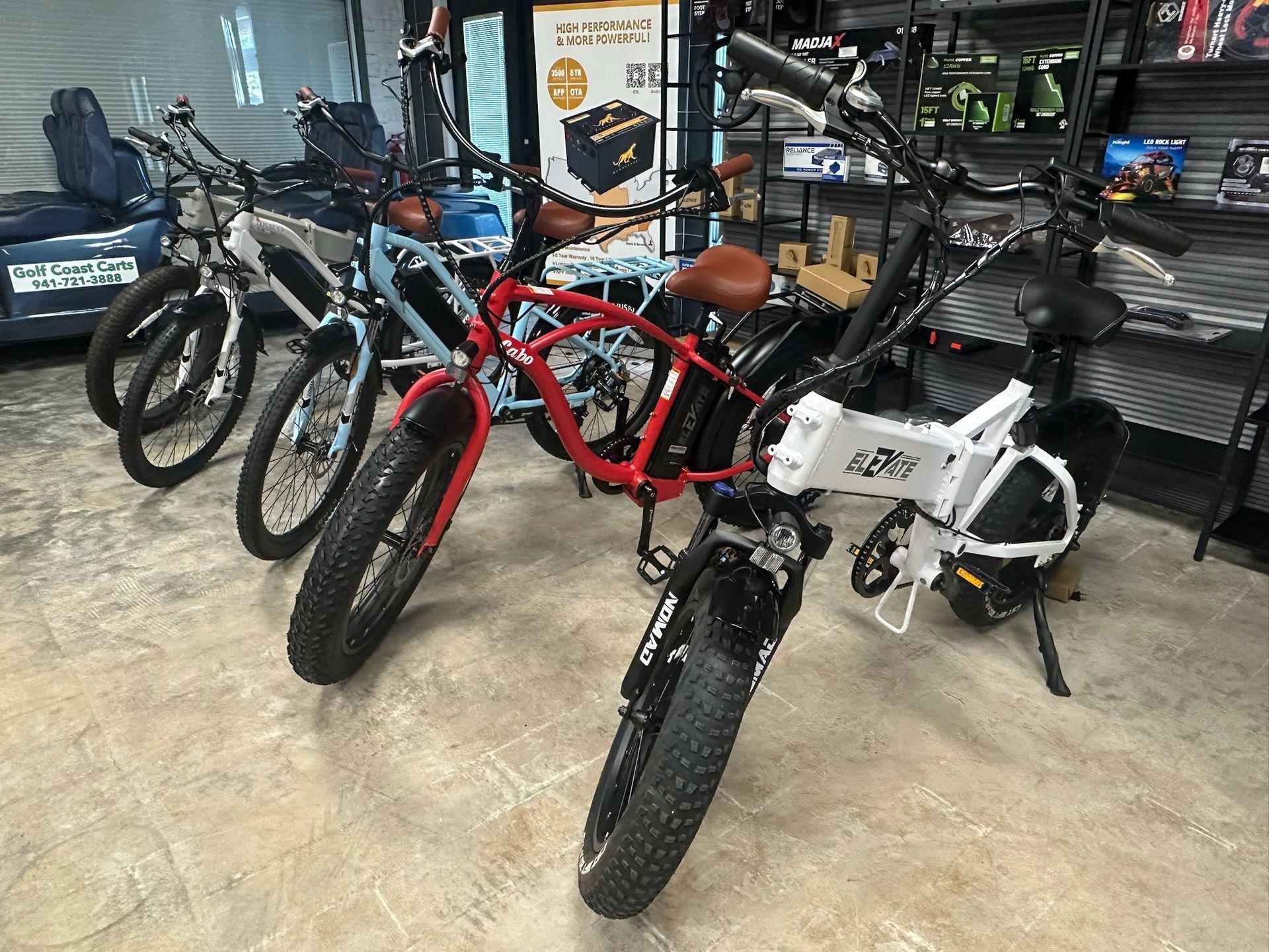 Fat-tire electric bikes displayed indoors, including red and white models on a showroom floor