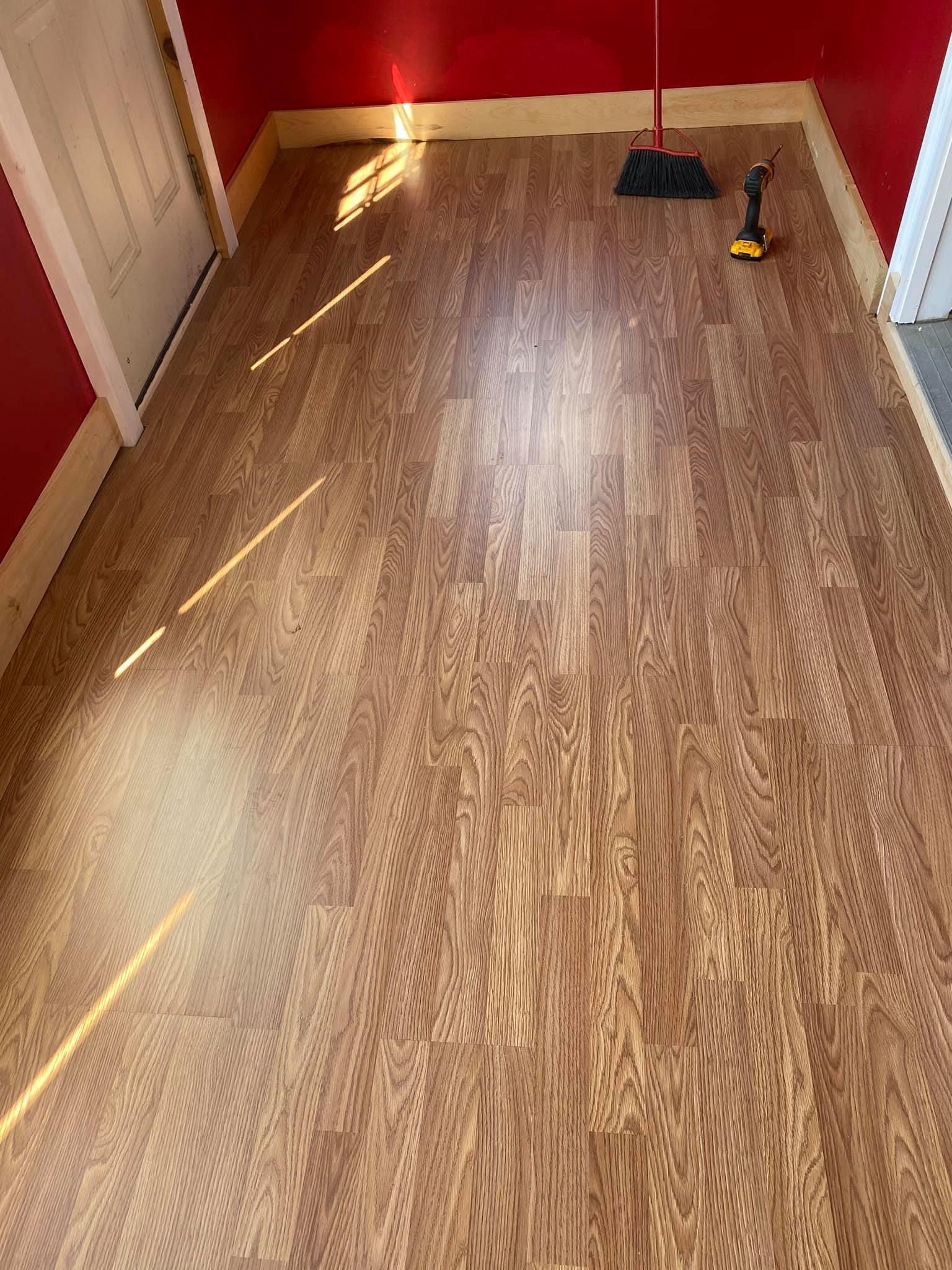 a wooden floor with a broom and drill on it in a room with red walls .