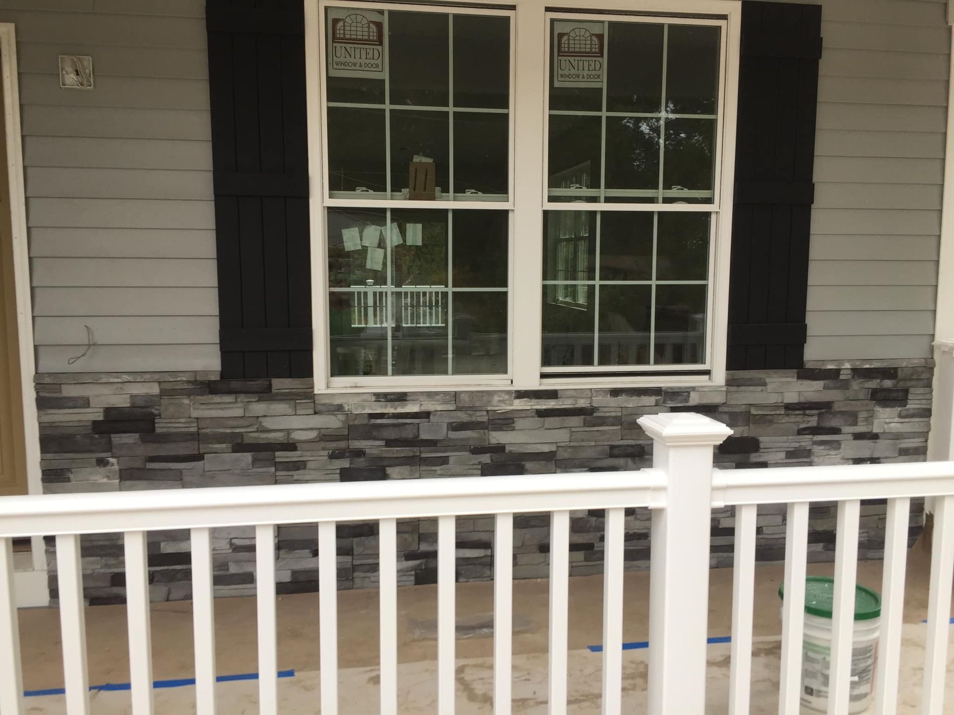 the front of a house with a white railing and a window .