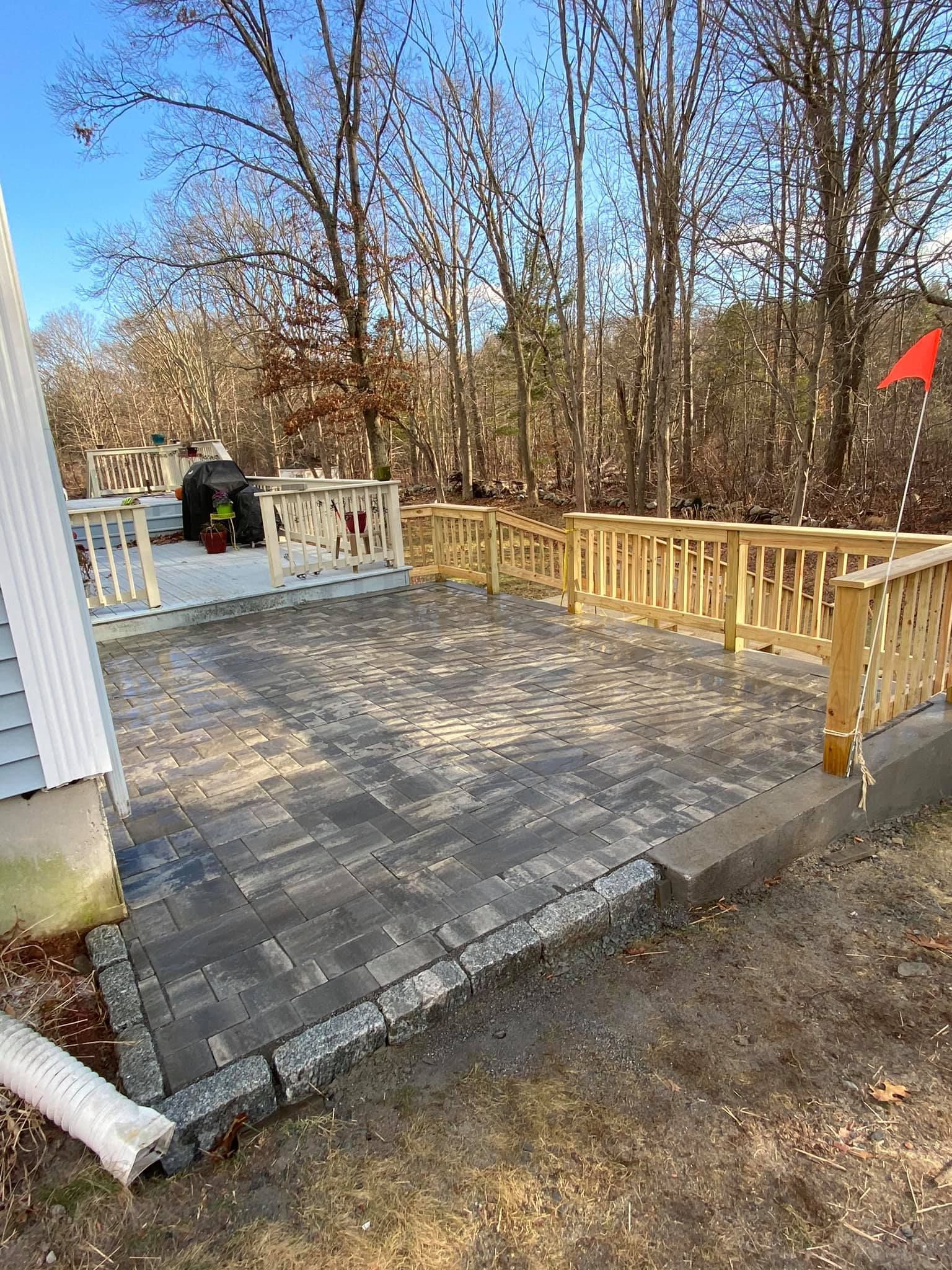 a patio with a wooden railing and trees in the background .