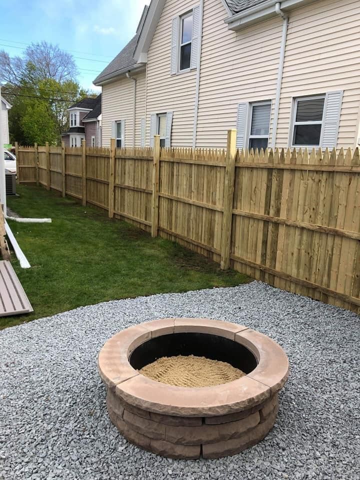 a fire pit in a backyard next to a wooden fence .