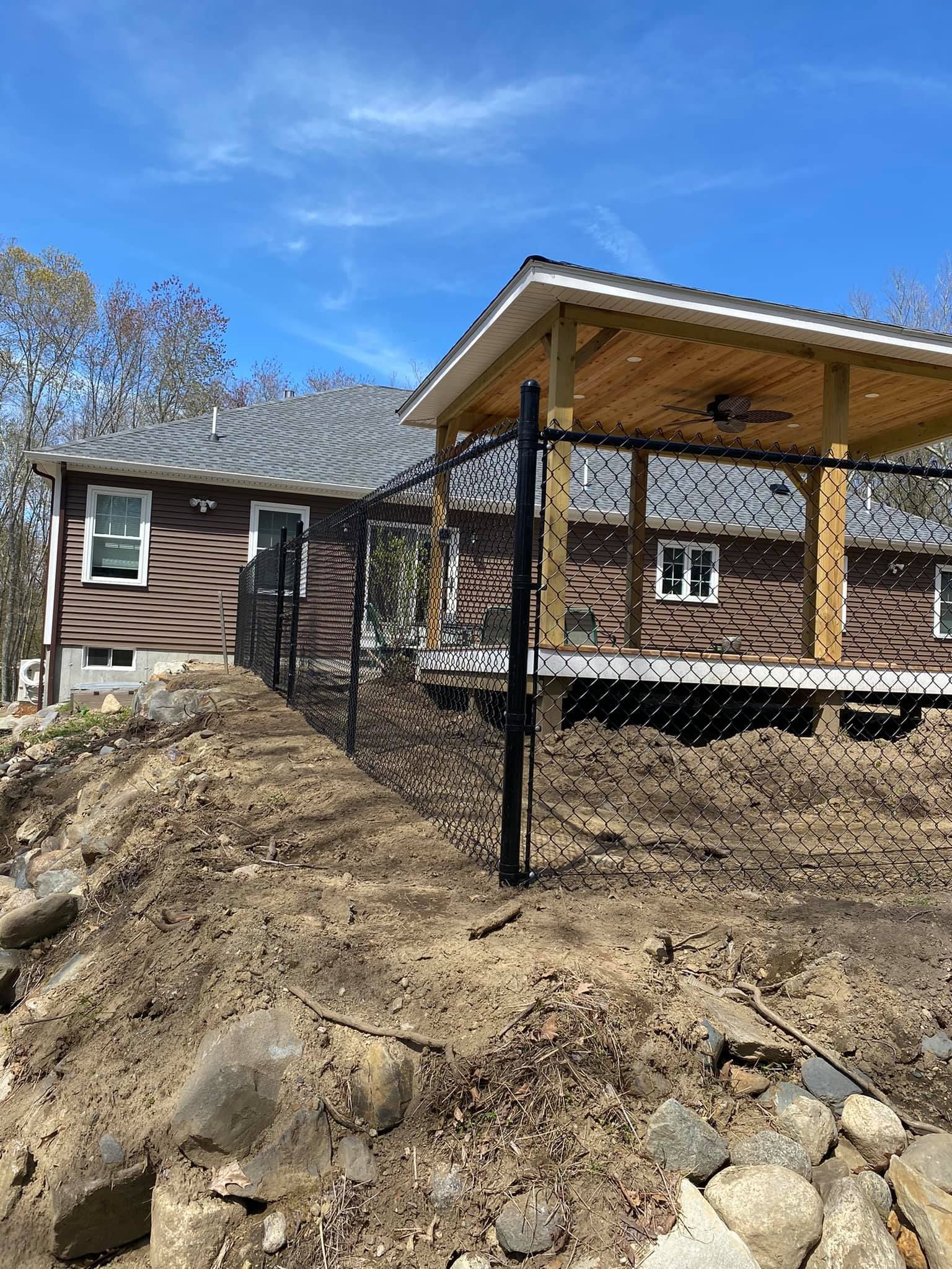 a house with a fence around it is sitting on top of a dirt hill .