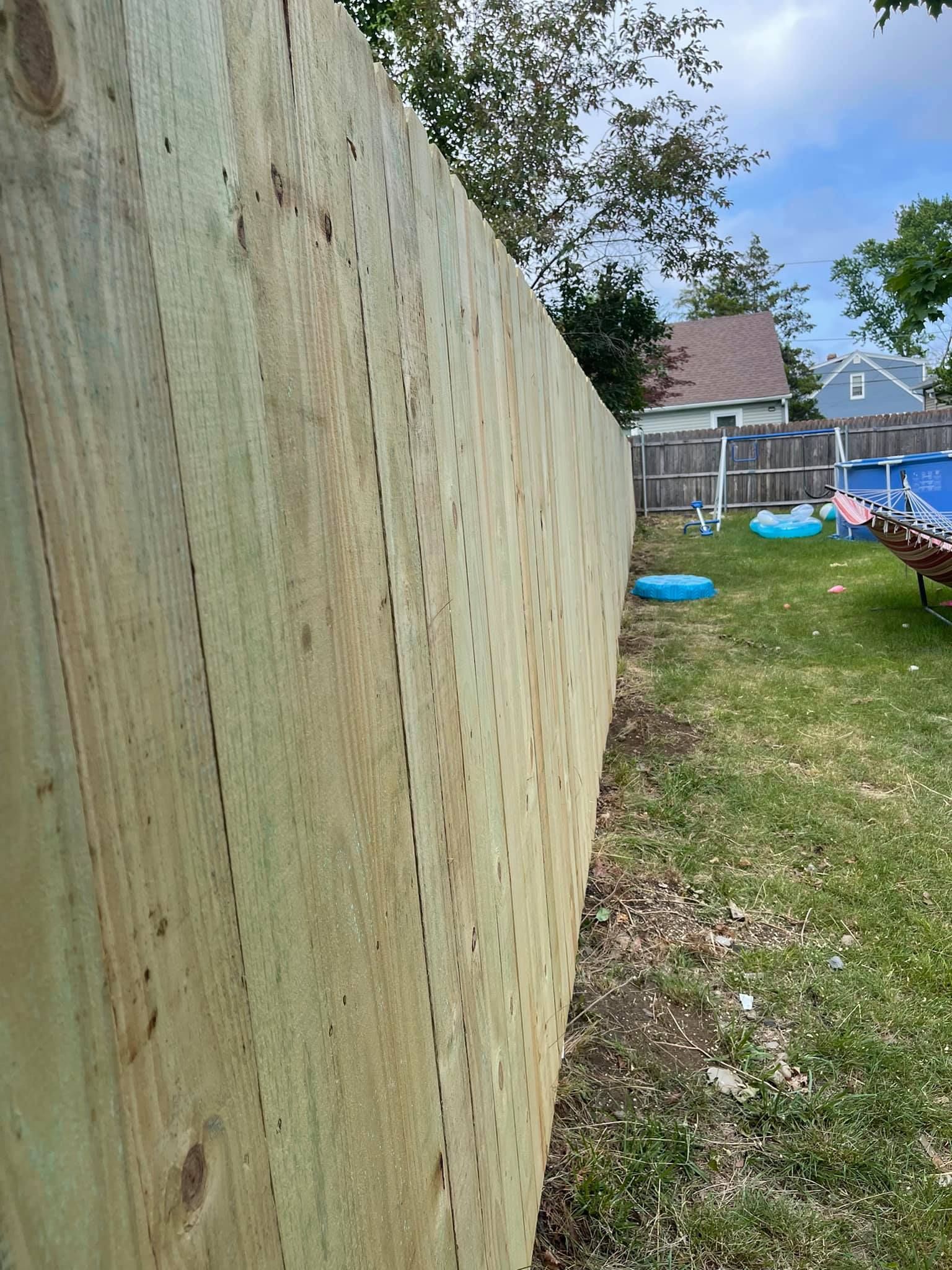 a wooden fence in a backyard next to a pool .