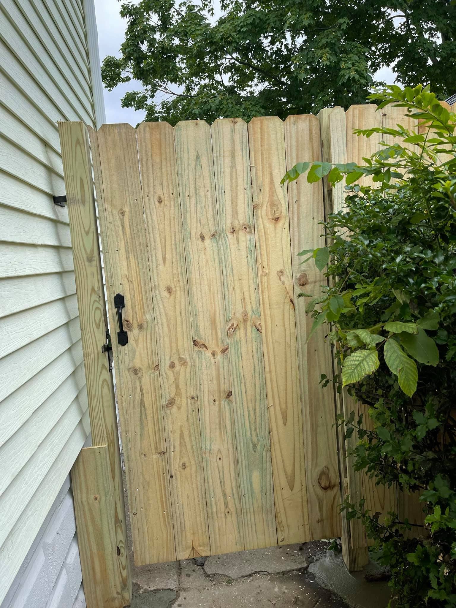 a wooden gate is sitting next to a house .