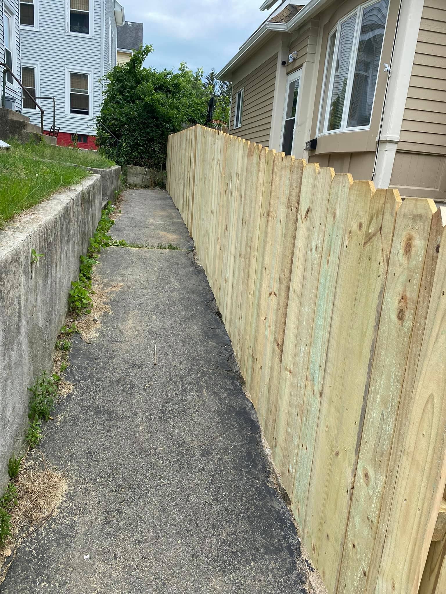a wooden fence along a sidewalk next to a house .