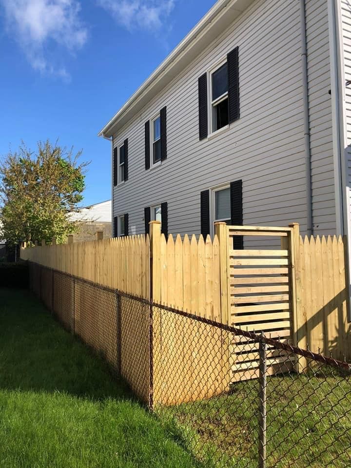 a wooden fence surrounds a chain link fence in front of a house .