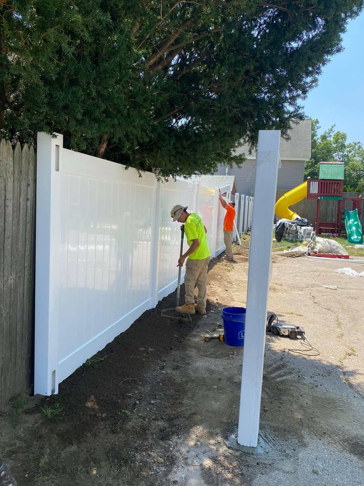 a man is painting a white fence in a backyard .
