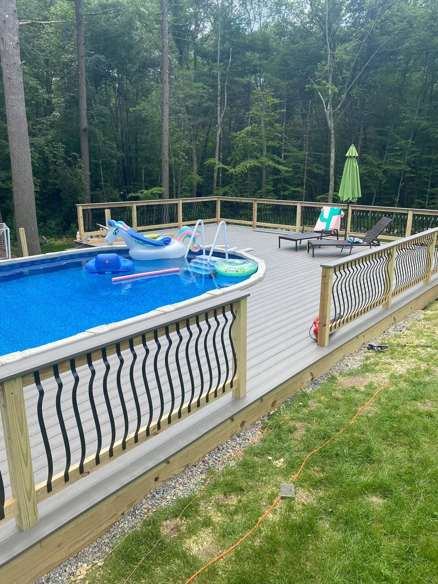 a large swimming pool is surrounded by a wooden deck .