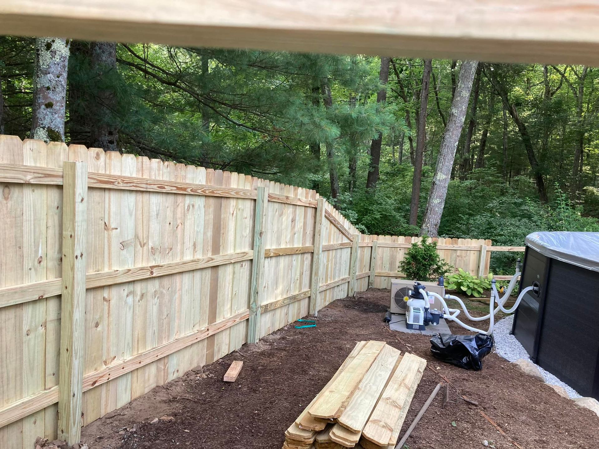 a wooden fence is being built in a backyard next to a pool .