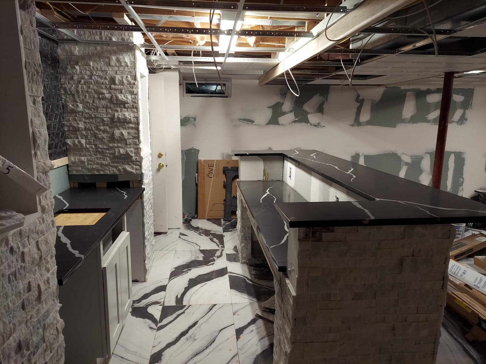 a kitchen in a basement under construction with marble counter tops .