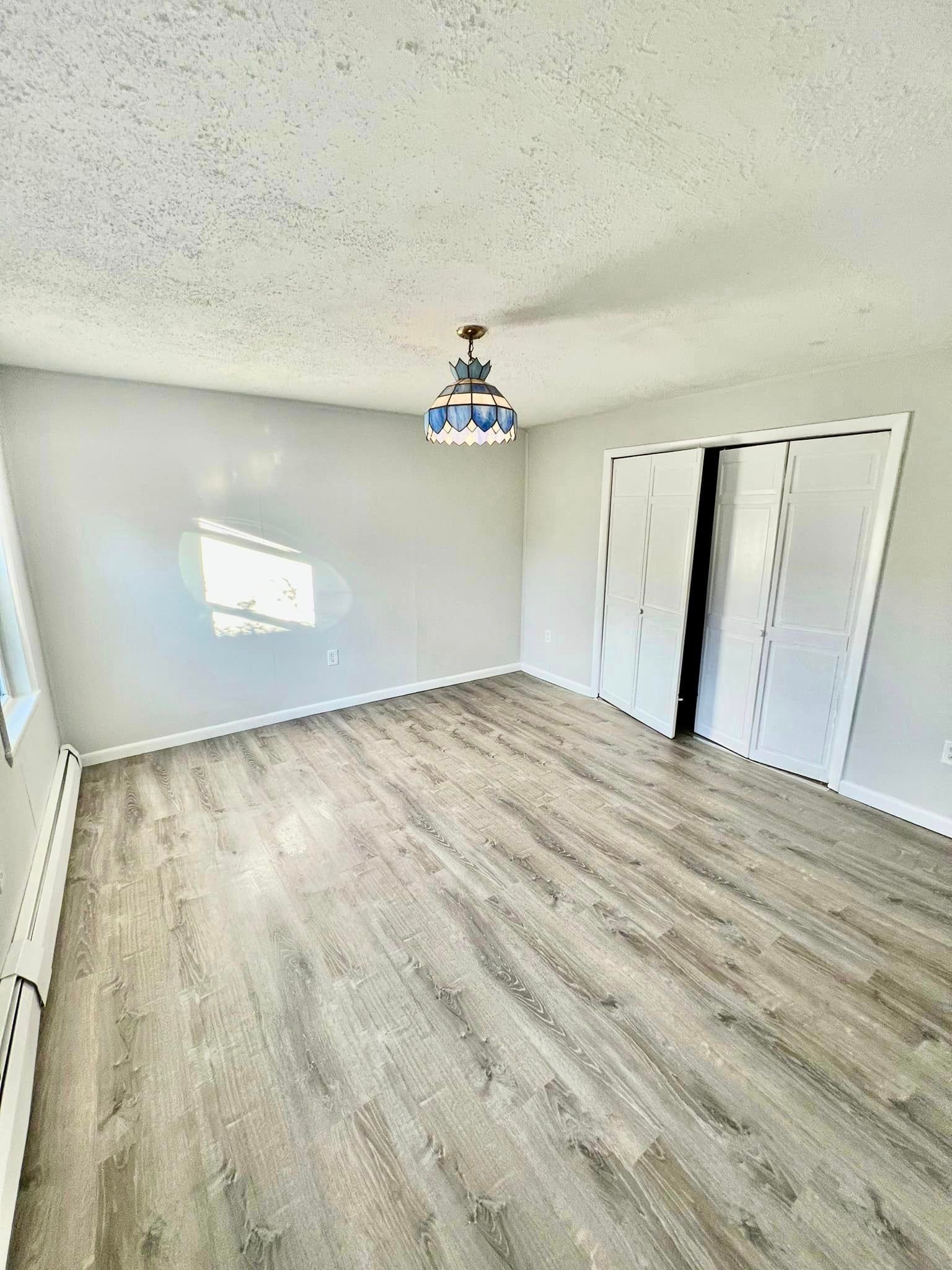 a large empty room with hardwood floors and a chandelier hanging from the ceiling .
