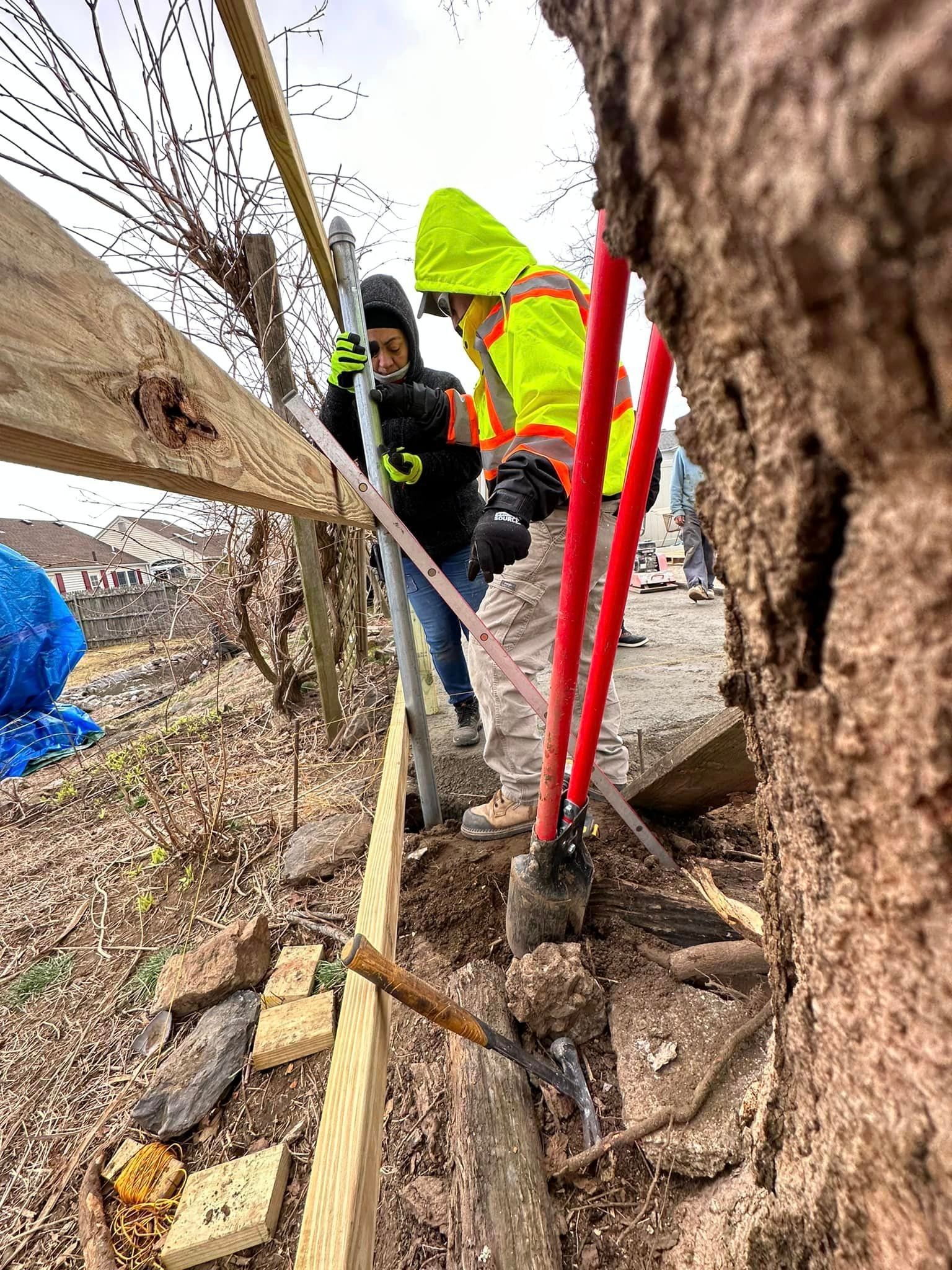 a group of people are working on a wooden fence .