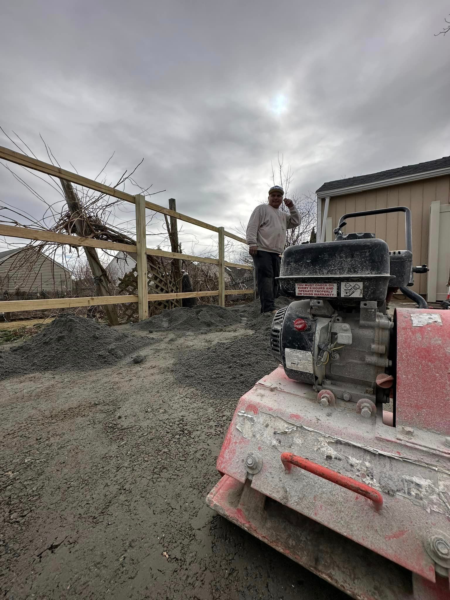 a man is standing next to a machine on a dirt road .