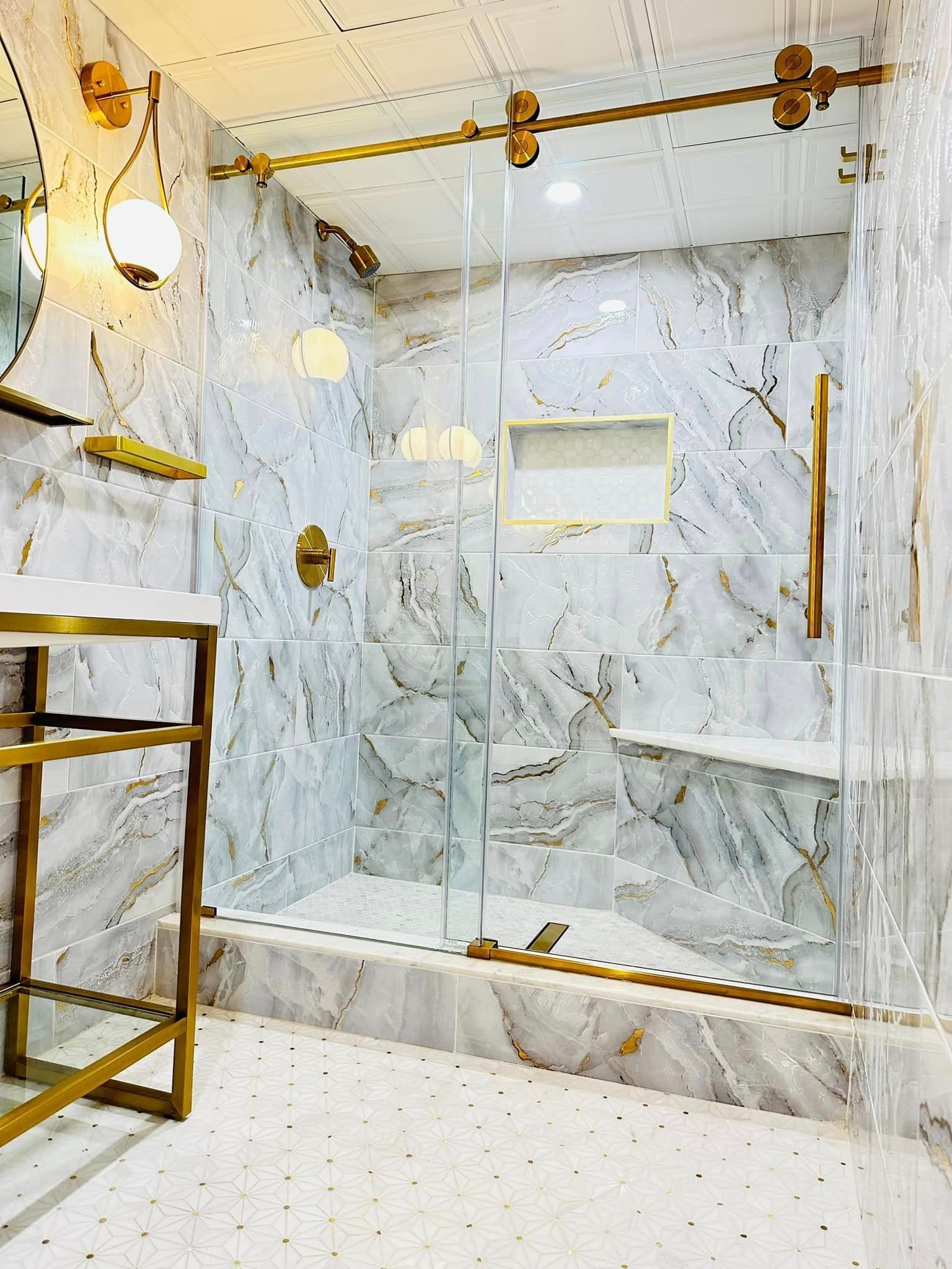 a bathroom with marble walls , a walk in shower , a sink and a mirror .