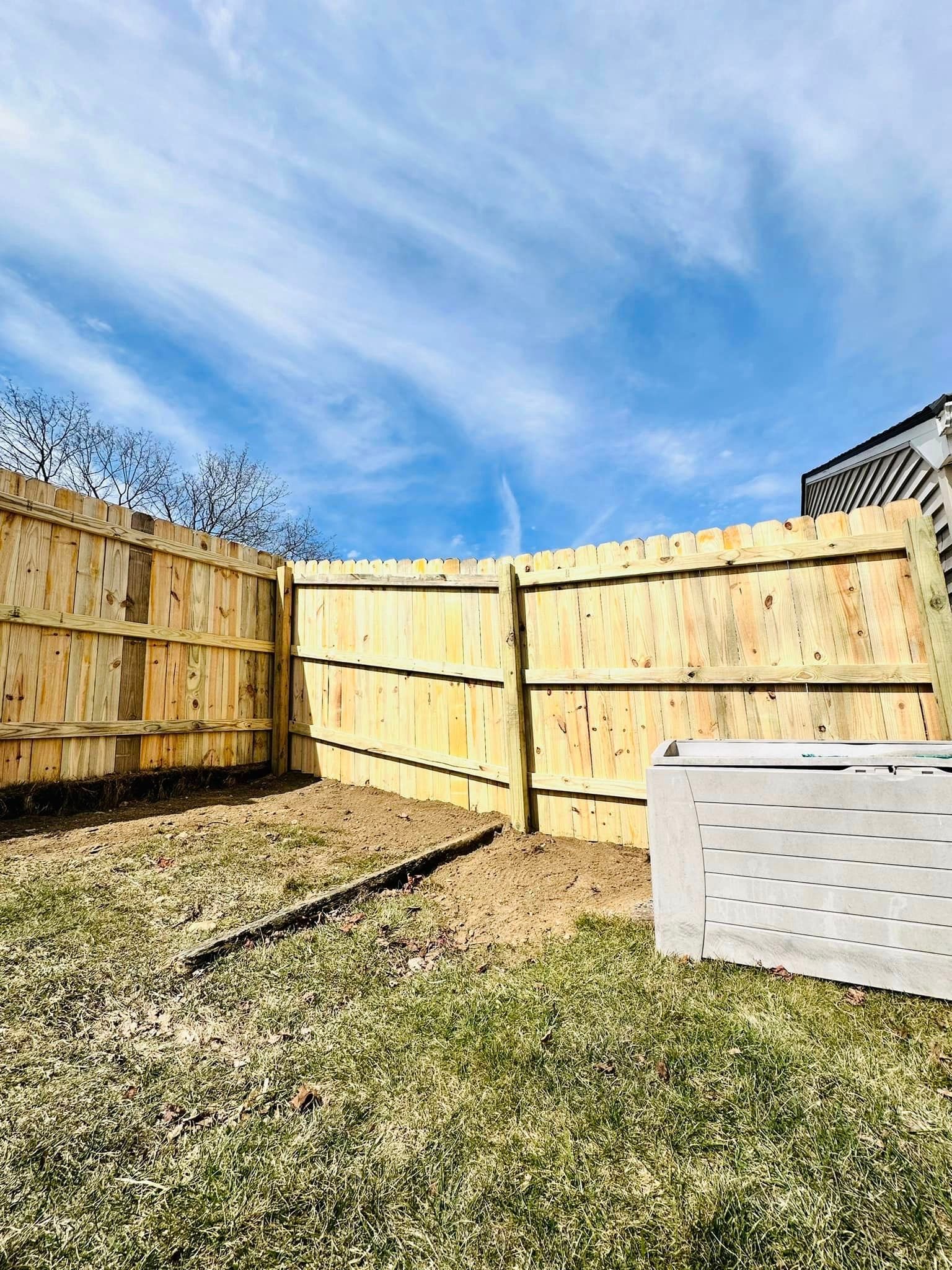 a wooden fence is in the middle of a grassy yard .