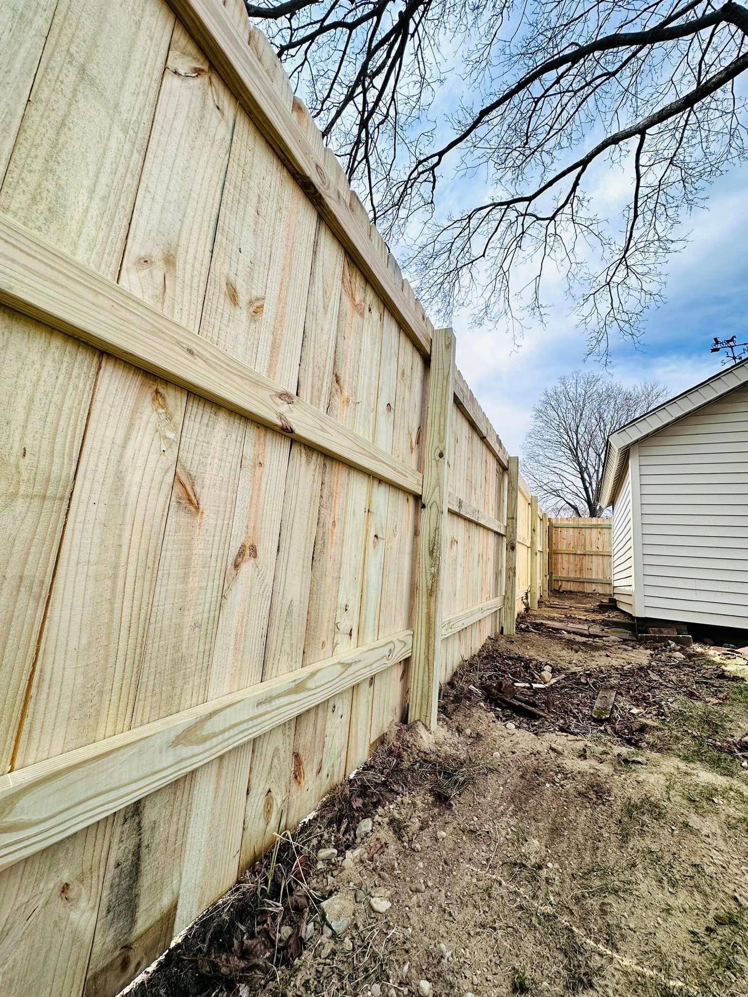 a wooden fence is being built in the backyard of a house .