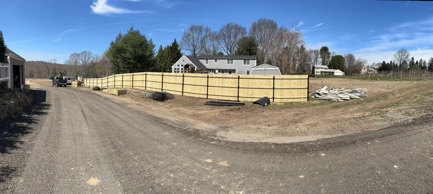 a wooden fence is being built on the side of a dirt road .