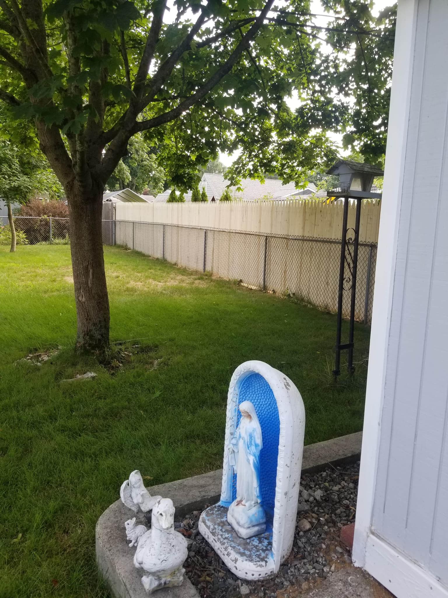 there is a statue of a woman in a garden next to a tree .