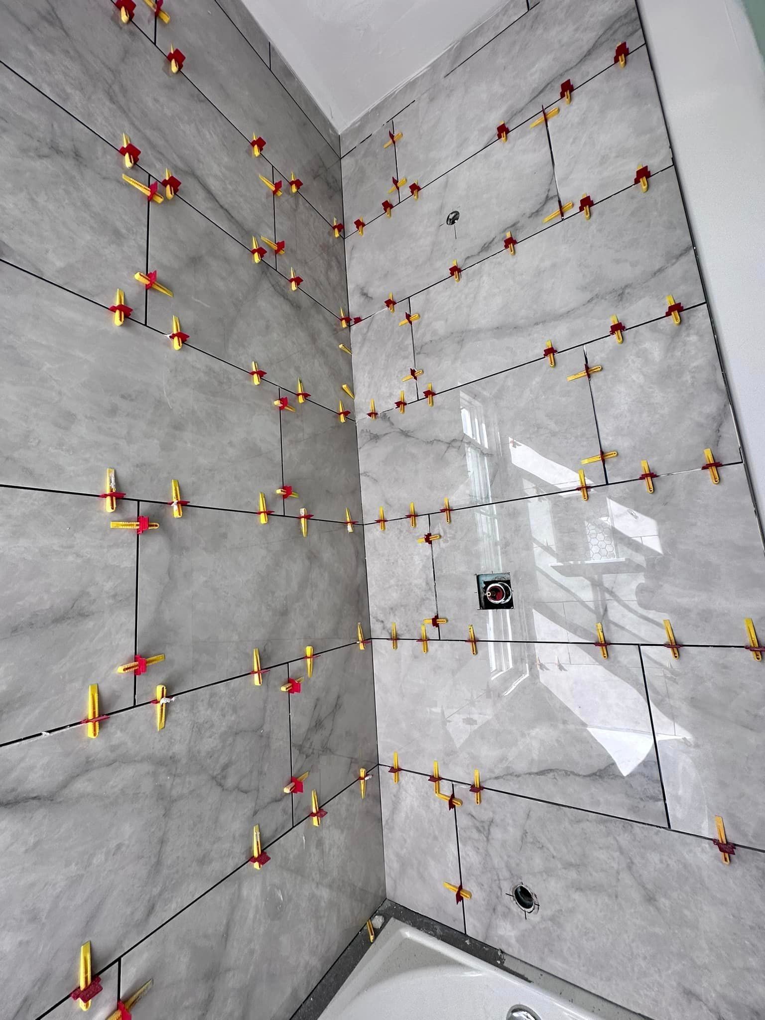 a bathroom with a bathtub and tiles being installed on the wall .