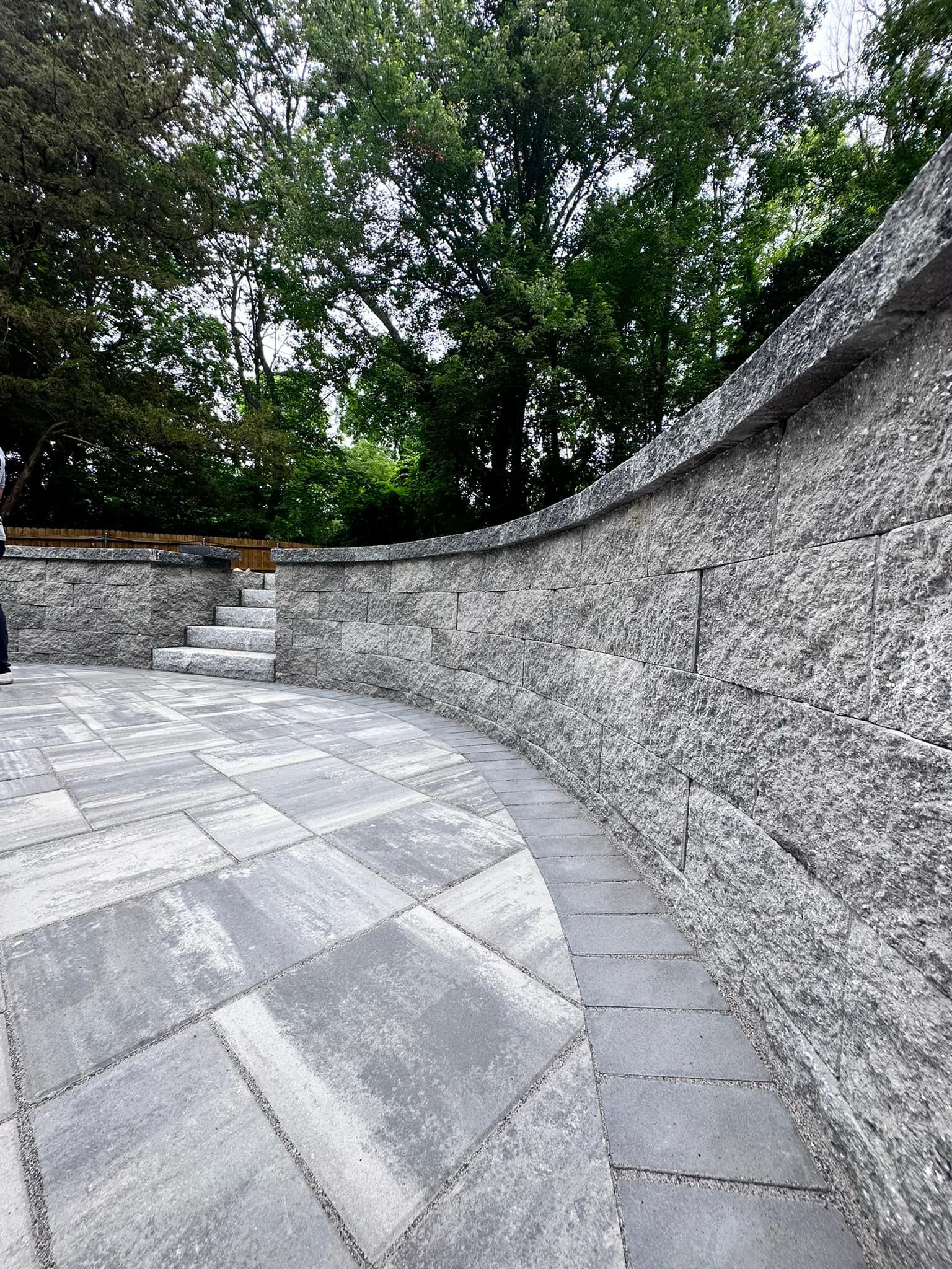 a stone wall with stairs leading up to it and trees in the background .