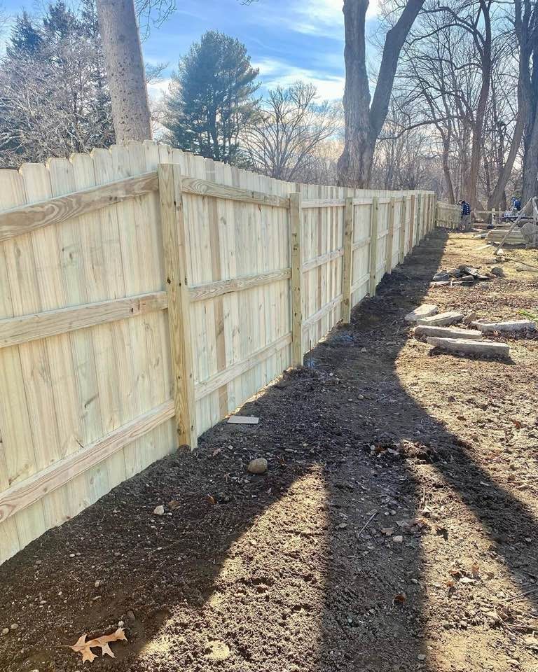a wooden fence is being built in a yard with trees in the background .