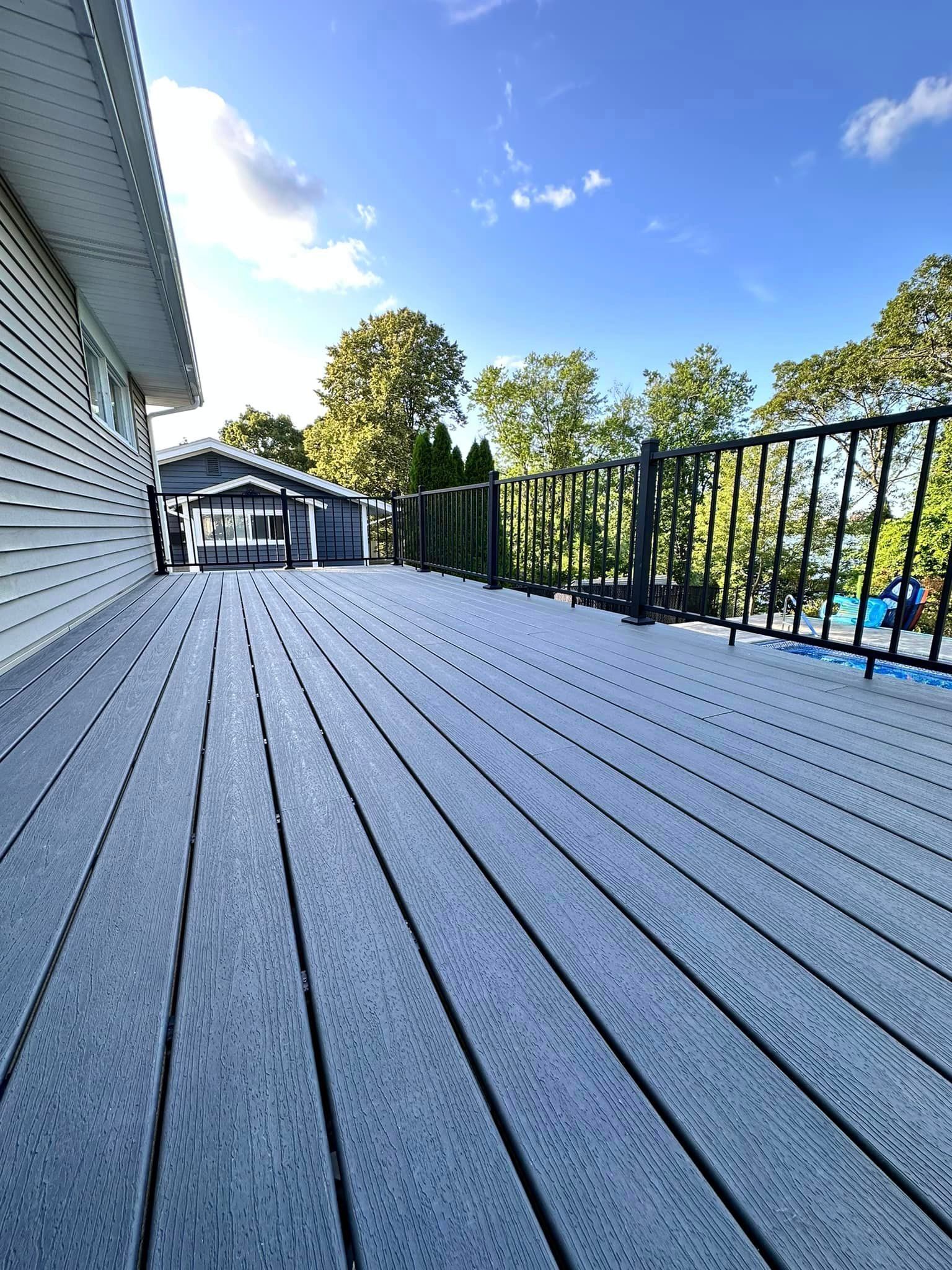 a large deck with a railing and a house in the background .