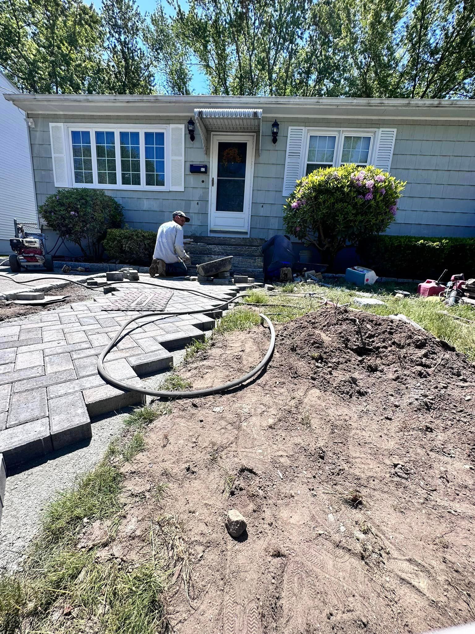 a man is working on a patio in front of a house .