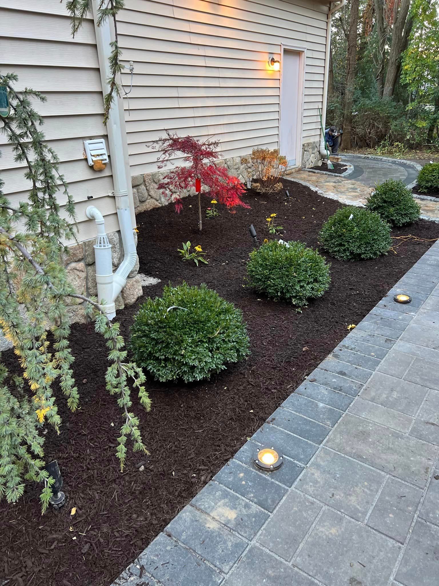 a brick walkway leading to a house with a garden in front of it .