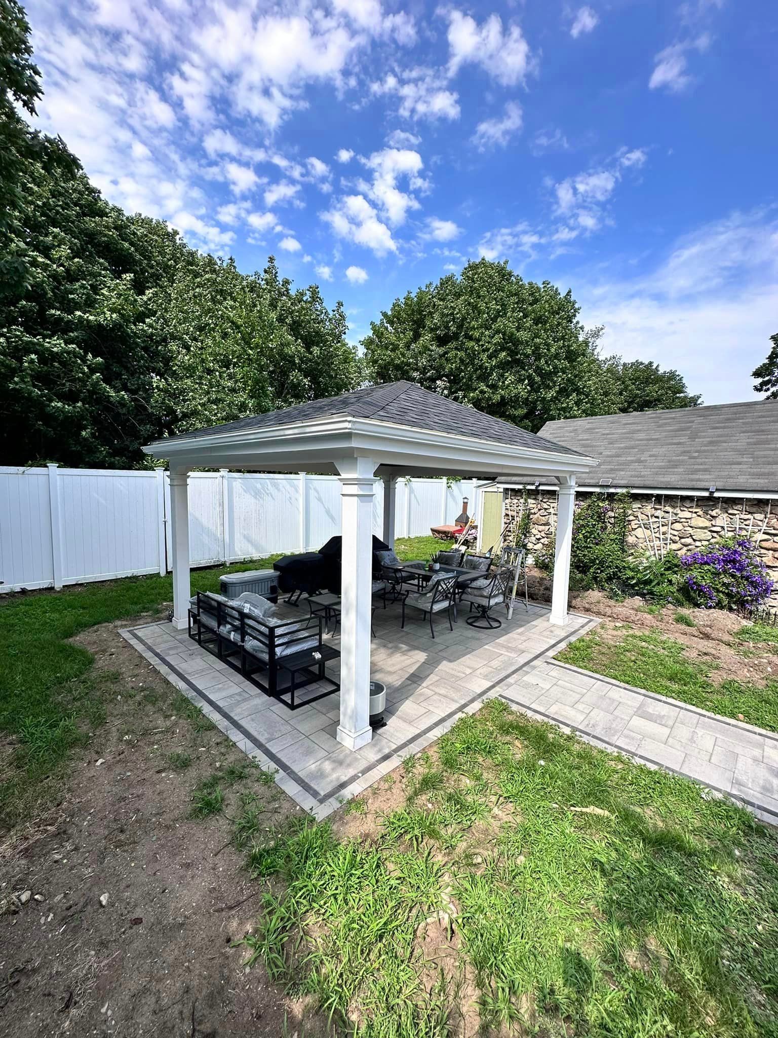 a white pergola with a table and chairs in the backyard of a house .