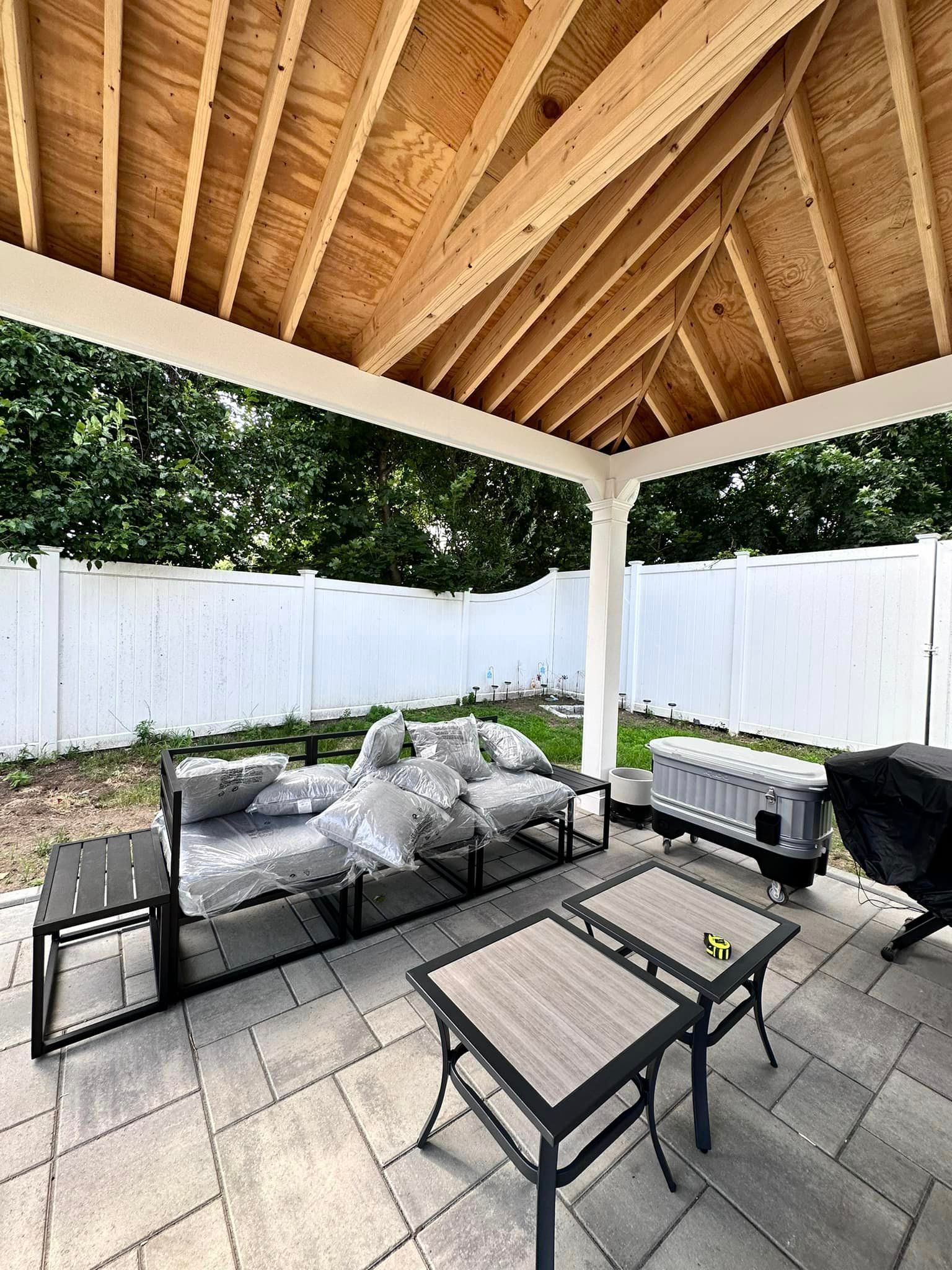 a patio with a couch , table and chairs under a gazebo .