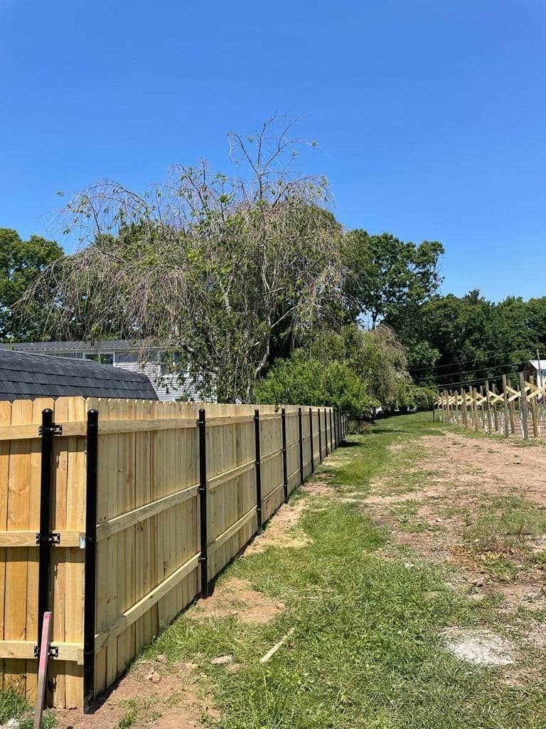 a wooden fence is sitting in the middle of a grassy field .