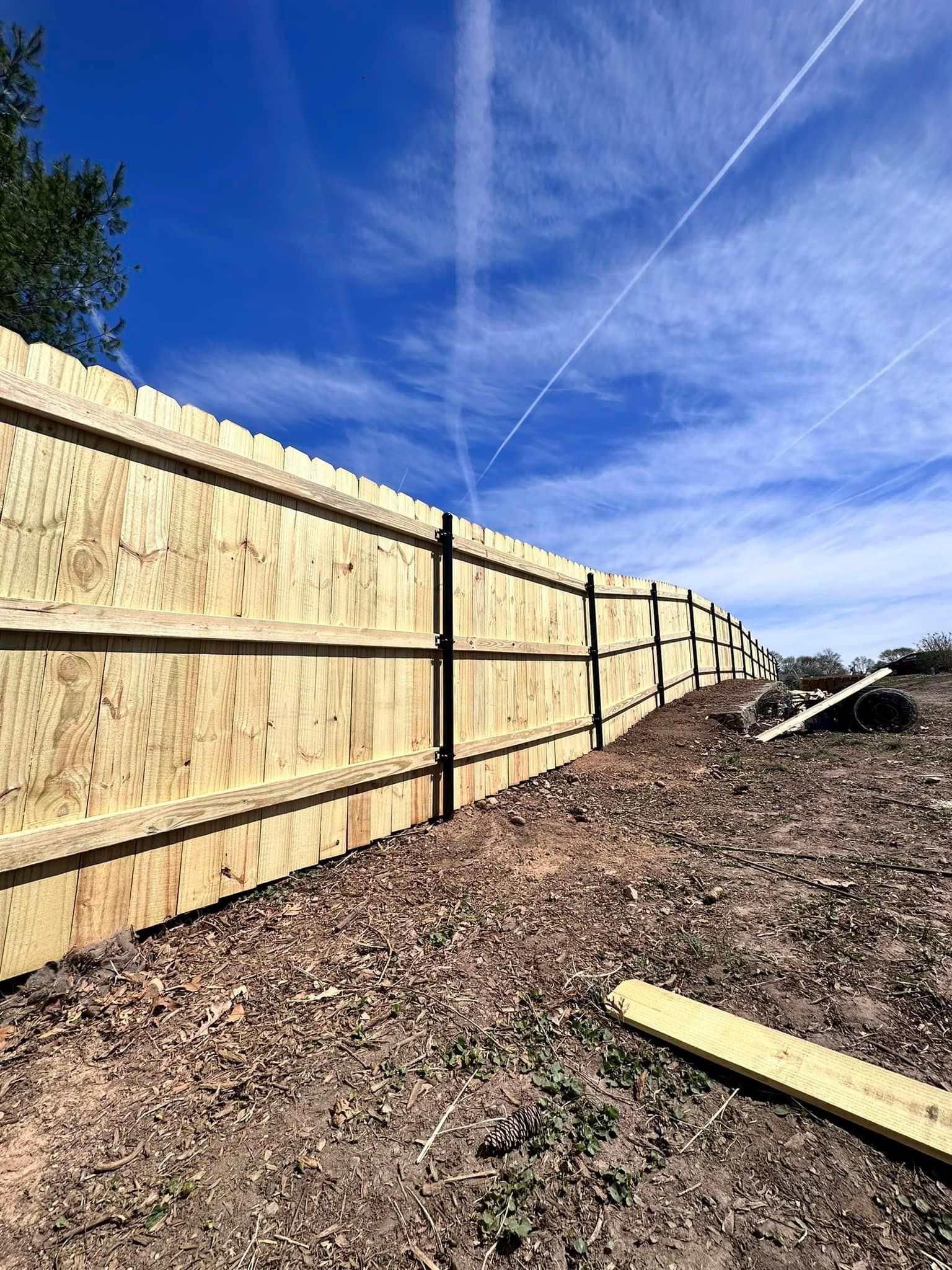a wooden fence is being built in the middle of a dirt field .