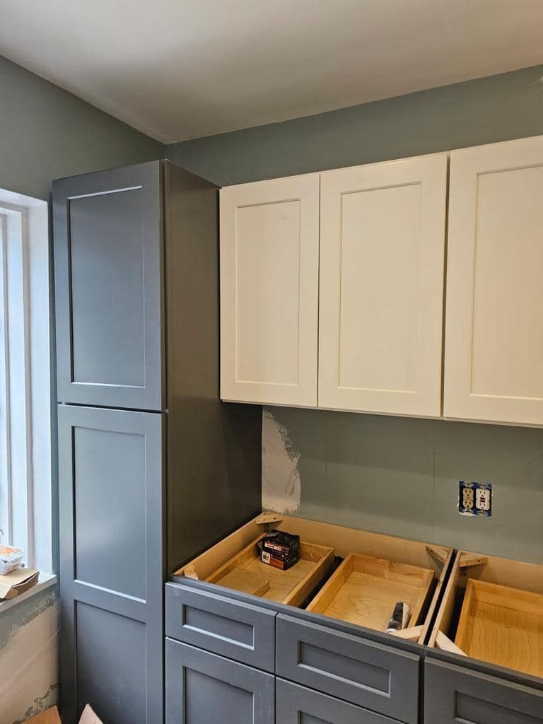 a kitchen with gray cabinets and white cabinets is being remodeled .