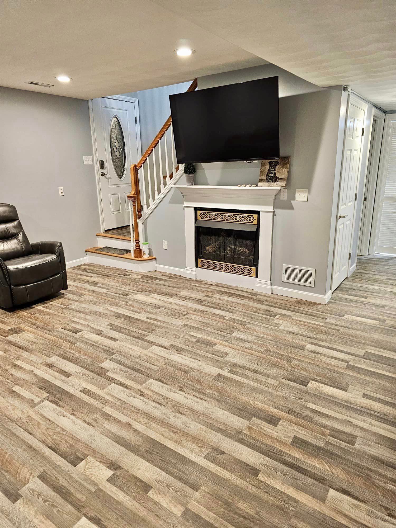 a living room with a fireplace , television , chair and stairs .
