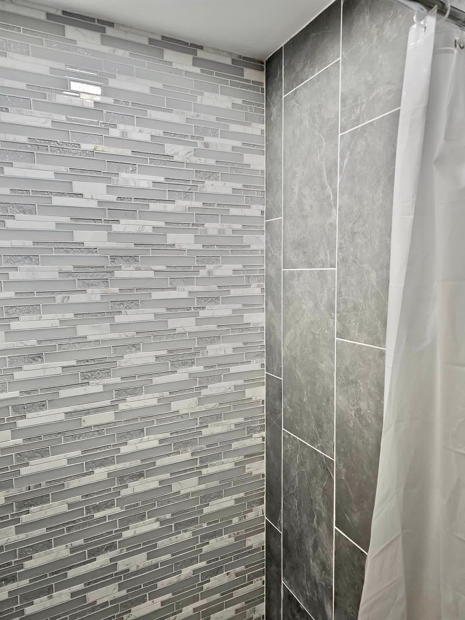a bathroom with a shower curtain and a tiled wall .